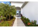 A walkway leads to a cozy sitting area on the front porch, surrounded by lush tropical plants at 14538 Barefoot Ln, Parrish, FL 34219