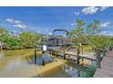 View of a boat lift on a canal, featuring a black pontoon boat, under a sunny blue sky at 467 Canal Rd # 467, Sarasota, FL 34242