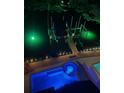 Aerial view of a backyard pool, hot tub, deck and boat lift illuminated with colorful lights at night at 467 Canal Rd # 467, Sarasota, FL 34242