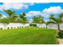 Spacious backyard with lush lawn, white fence, and tropical landscaping at 4817 Sarasota Ave, Sarasota, FL 34234