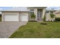 House exterior showcasing a light beige color scheme, white garage doors, and landscaping at 16381 Cape Horn Blvd, Punta Gorda, FL 33955