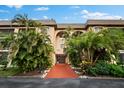 Beautiful condo building showcasing lush landscaping and a welcoming red-carpeted entrance at 3700 S Osprey Ave # 214, Sarasota, FL 34239