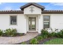 A home's entrance features a gray door and brick walkway at 12413 Parigi Way, Sarasota, FL 34238