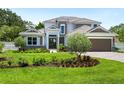 Two-story home with a three-car garage, stone accents, and lush landscaping at 1637 Hyde Park St, Sarasota, FL 34239