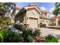 Tan three-story townhome with attached garage, landscaping, and walkway at 8256 Enclave Way # 101, Sarasota, FL 34243