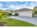 Single story home with light colored vinyl siding, two car garage, and lush lawn at 1057 Meadow Breeze Ln, Sarasota, FL 34240