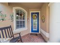 Inviting front entry with a blue door, brick flooring, and rocking chair at 6023 Wingspan Way, Bradenton, FL 34203