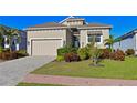 Tan single-story house with a paved driveway and lush landscaping at 6248 Champions Row, Bradenton, FL 34210