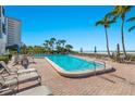 Beautiful pool and beach at beachfront condo with palm trees and lounge chairs on brick paver deck on sunny day at 1102 Benjamin Franklin Dr # 409, Sarasota, FL 34236