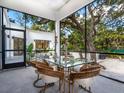 Bright sunroom with glass walls, a glass dining table and wicker chairs at 1331 Quail Dr, Sarasota, FL 34231