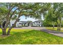 Beautiful white home with black trim nestled among mature trees and lush green lawn at 2410 Slough Rd, Sarasota, FL 34240