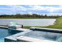 A closer view of the pool and spa featuring mosaic tile accents and a serene lake view at 16606 Barnwood Pl, Bradenton, FL 34211