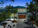 Modern two-story home with a teal roof, wood garage door, meticulous landscaping and paver driveway at 2425 Floyd St, Sarasota, FL 34239