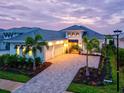 Elegant home showcasing a beautifully paved driveway, lush landscaping, and a charming facade under a twilight sky at 8332 Sea Glass Ct, Sarasota, FL 34240