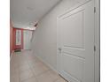 Hallway with pink walls, tiled floor, and a white door at 17014 Wave Tressle Pl, Wimauma, FL 33598