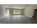 An empty living room featuring modern gray floors, a large window with views, and access to a backyard patio at 3249 Vickers Ln, North Port, FL 34286