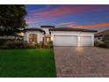 White two-story house with a brick driveway and a three-car garage at 13627 American Prairie Pl, Lakewood Ranch, FL 34211