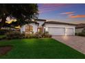 Two-story house with a brick driveway and three-car garage, at sunset at 13627 American Prairie Pl, Lakewood Ranch, FL 34211
