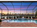 Relaxing screened-in pool area featuring a water view, fountains, fire feature and brick pavers; ideal for outdoor enjoyment at 5058 Surfside Cir, Lakewood Ranch, FL 34211
