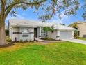 One-story home with gray exterior, two-car garage, and lush landscaping at 6929 Stetson Street Cir, Sarasota, FL 34243