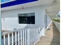 Exterior view showing a hallway with white walls and railings, a window, and palm trees at 475 Benjamin Franklin Dr # 209, Sarasota, FL 34236