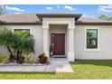 House entrance featuring a red door and neat landscaping at 7677 Meroni Blvd, North Port, FL 34291