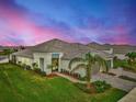 Single-story home with tile roof, landscaped yard, and two-car garage at sunset at 12496 Palatka Dr, Venice, FL 34293