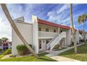 White building with red roof, stairs, and palm trees at 1801 Gulf N Dr # 222, Bradenton Beach, FL 34217