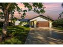Stunning modern home exterior at dusk, featuring a wood-paneled garage door and beautiful landscaping at 1899 Buccaneer Cir, Sarasota, FL 34231
