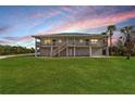 Two-story house exterior, showcasing a spacious lawn and sunset views at 445 Horseshoe Loop Rd, Terra Ceia, FL 34250
