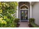 Elegant entryway with double doors, a brick walkway, and lush greenery at 12240 Thornhill Ct, Lakewood Ranch, FL 34202