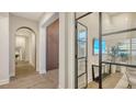 Elegant hallway with arched doorways, wood floors, and glass-walled office at 19439 Beacon Park Pl, Bradenton, FL 34202