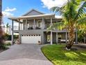 Two-story home with gray siding, white garage door, balcony, and tropical landscaping at 3460 Flamingo Ave, Sarasota, FL 34242