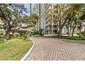 Brick driveway leading to a modern building, surrounded by lush landscaping at 1111 N Gulfstream Ave # 6B, Sarasota, FL 34236