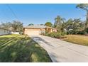 Tan house with driveway, two-car garage, and lush landscaping at 3623 Monday Ter, North Port, FL 34286