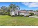 Tan house with a two-car garage, palm trees, and well-kept lawn at 7153 Drewrys Blf, Bradenton, FL 34203