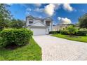 Two-story house with a white exterior, a brick driveway, and lush landscaping at 11216 Coralbean Dr, Lakewood Ranch, FL 34202