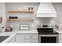 Bright kitchen featuring stainless steel appliances, floating shelves, and light gray subway tile at 4204 126Th W St # 506, Cortez, FL 34215