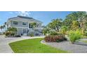 Two story home with gray siding, metal roof, and landscaped yard at 7418 Westmoreland Dr, Sarasota, FL 34243