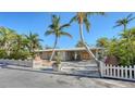 Single story home with palm trees and white picket fence at 834 Jungle Queen Way, Longboat Key, FL 34228