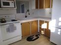 Galley kitchen with white appliances and wood cabinets at 1208 44Th Avenue E Dr, Ellenton, FL 34222