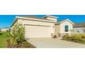 House exterior featuring beige siding, a two-car garage, and landscaping at 15813 6Th E Ave, Bradenton, FL 34212