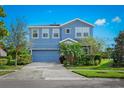 Two-story house with blue exterior, gray garage door, and landscaping at 6138 Colmar Pl, Apollo Beach, FL 33572