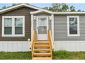 Steps leading to the front door of a manufactured home with a wood-tone deck at 12512 Hicks Rd, Hudson, FL 34669