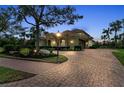 Expansive brick paver driveway leading to a beautiful home surrounded by manicured landscaping at 3408 Founders Club Dr, Sarasota, FL 34240