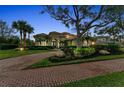 Beautiful home exterior with manicured landscaping, a brick driveway, and palm trees at 3408 Founders Club Dr, Sarasota, FL 34240