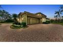 Side view of the home showcasing a two car garage and brick paver driveway at 3408 Founders Club Dr, Sarasota, FL 34240