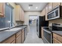 Galley kitchen with light wood cabinets, dark countertops, and stainless steel appliances at 4207 Overture Cir, Bradenton, FL 34209