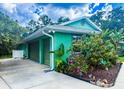 View of the two-car garage with matching doors and landscaping, under blue skies and white puffy clouds at 1496 Palm View Rd, Sarasota, FL 34240
