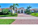 One-story home with red tile roof, palm trees, and a brick driveway at 25261 Spartina Dr, Venice, FL 34293